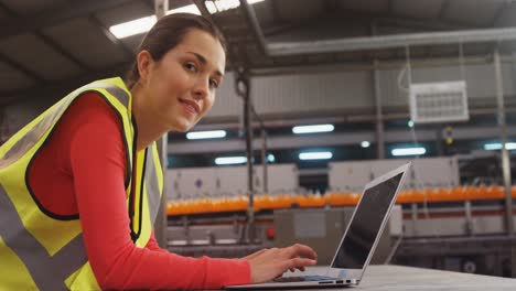 supervisor femenino usando una computadora portátil cerca de la línea de producción