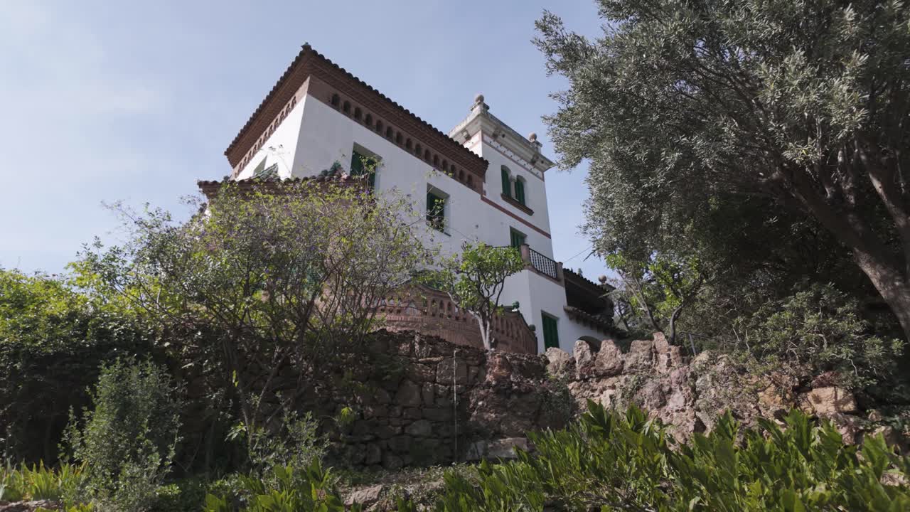 Historic white walled Casa Trias surrounded by greenery in Park Güell Barcelona Spain