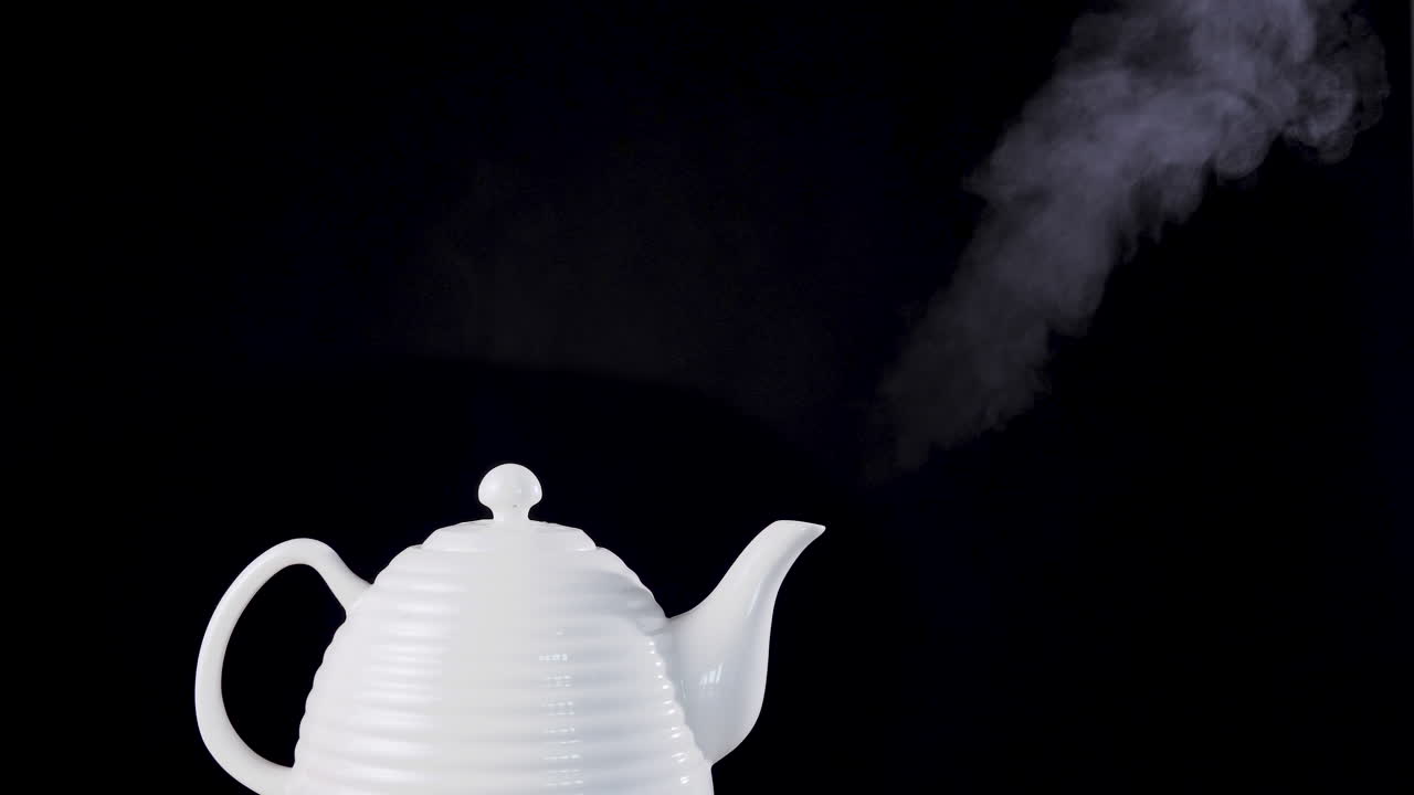 Tea pot on black background with boiling water