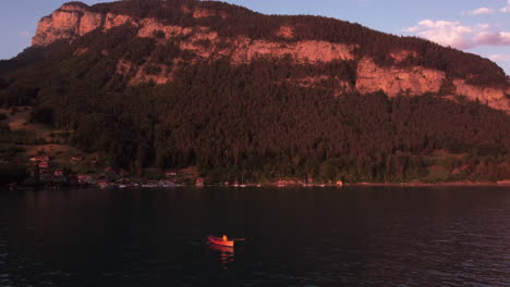 Circling-around-a-red-canoeing-boat-on-a-romantic-mountain-lake-during-sunset