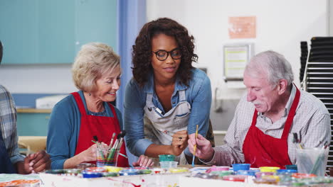 group of retired seniors attending art class in community centre with teacher