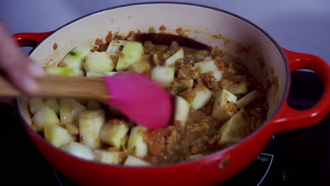 Stirring-in-green-raw-papaya-into-a-cast-iron-pot-Green-and-ripe-yellow-organic-fresh-papaya-pawpaw