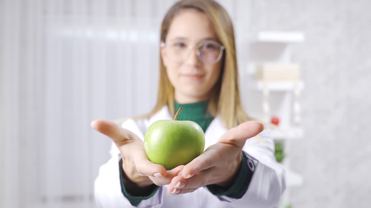 la nutricionista positiva está mostrando la manzana verde para una alimentación saludable.