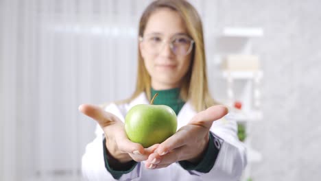 Positive-dietitian-woman-is-showing-green-apple-for-healthy-eating.