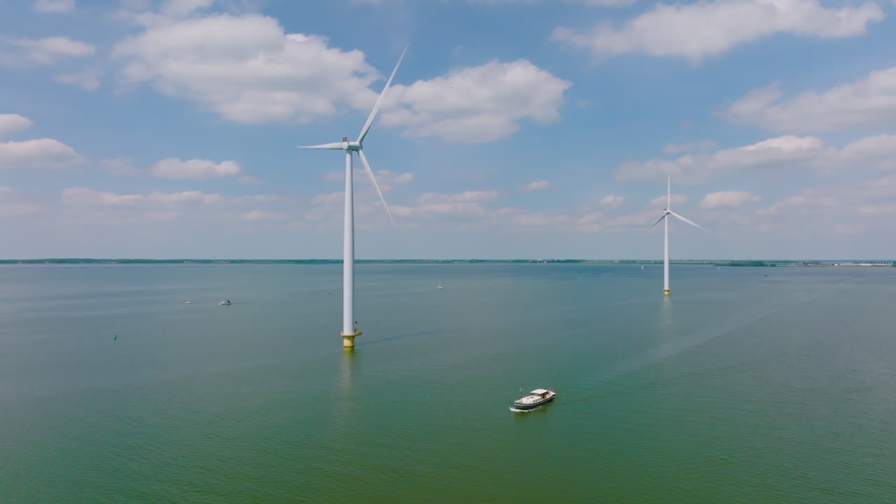 aerial view of a row of wind turbines crossed by a fishing boat in Holland