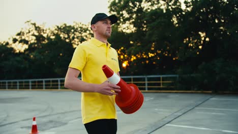 Close-up-shot-of-a-man-in-a-yellow-T-shirt-and-a-cap-wears-orange-road-cones.-Motorcycle-school-teacher