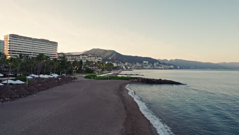 Drone-video-showcasing-the-vast-and-beautiful-coastline-of-Puerto-Vallarta,-flying-along-the-coast-with-the-hotels-zone-and-the-sea