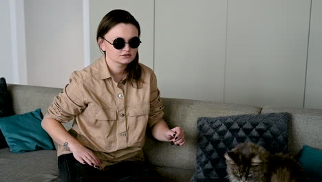 femme aveugle à lunettes de soleil assise sur un canapé à la maison et caressant son chat 2