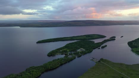 Lujuriosa-Isla-Mendigar-Durante-La-Colorida-Puesta-De-Sol-En-Irlanda-Del-Norte,-Alta-Antena-Hacia-Atrás