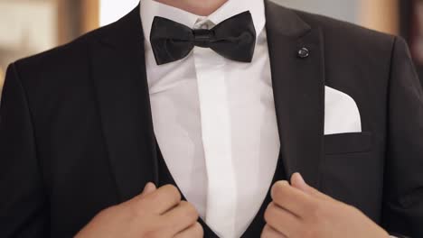 Handsome-groom-businessman-wearing-gray-jacket-indoors-at-barber-shop,-white-shirt-with-black-tie