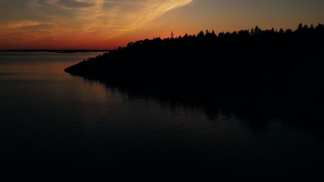 drone rising over forest, revealing idyllic archipelago, finland, summer sunset