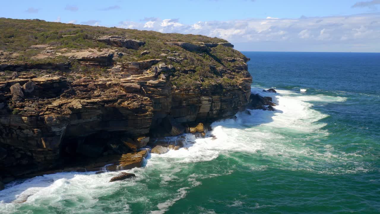 Waves Impacting The Coastal Cliffs During Daytime At Royal National Park In New South Wales, Australia - aerial drone shot