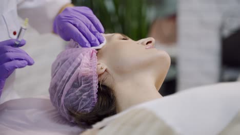 beauty clinic. beautician hands in gloves making face anti-aging injection in a female neck. a woman gets beauty facial cosmetology procedure. botox.