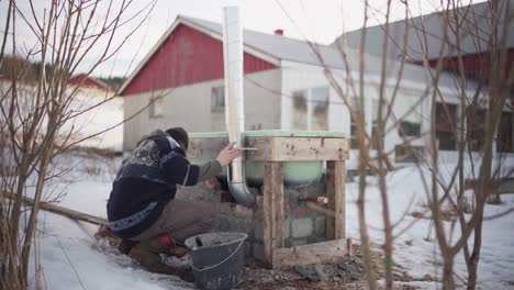 the man is fastening the chimney in its position on the diy hot tub - static shot