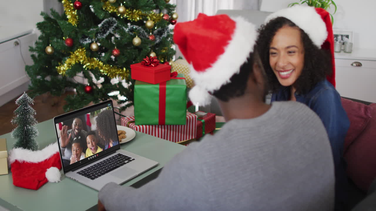 feliz pareja afroamericana en videollamada en computadora portátil con la familia en tiempo de navidad