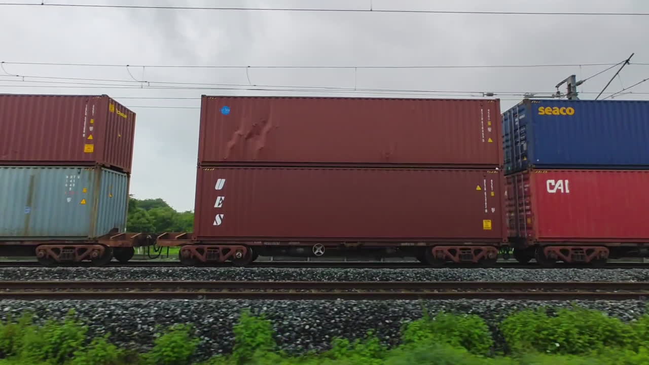 View from another train of freight train with two levels of colorful containers traveling on Indian railroads, vibrant colors of Indian transport.