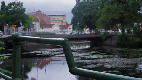 cerca de mano de un carril verde por el río viskan en borås suecia con un puente en el fondo con un coche y árboles y edificios en la ciudad