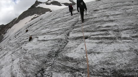 mountaineers walk on a steep glacier in the swiss alps mountains to find crystal in the rock with their equipement, helmet