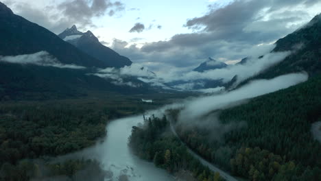 moody scenery in cloud filled valley in british colombia filled with pine tree forest, aerial