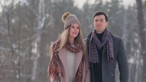 young married couple in love walking in the winter forest. a man and a woman look at each other laughing and smiling in slow motion. valentine's day love story.