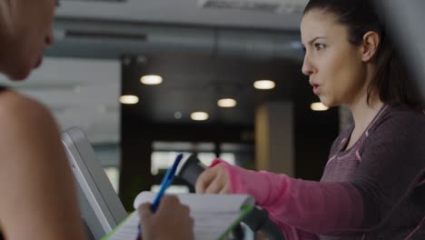 Handheld-view-of-personal-trainer-guiding-woman-at-gym