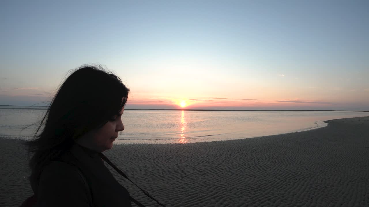 chica con cámara caminando en la playa por la puesta de sol cerca de cámara lenta