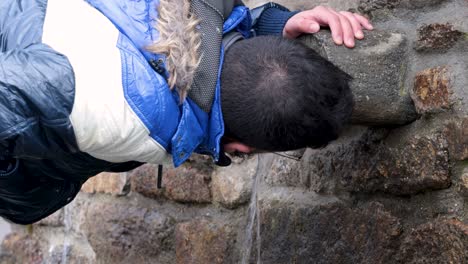 Drinking-water-from-the-water-spout-of-a-stone-fountain,-outdoors-video