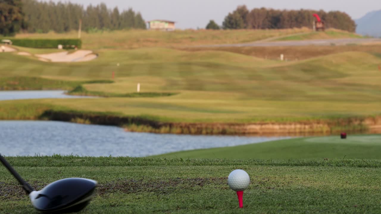 Golf driver hits ball from tee, wide fairway view, natural daylight, smooth camera pan