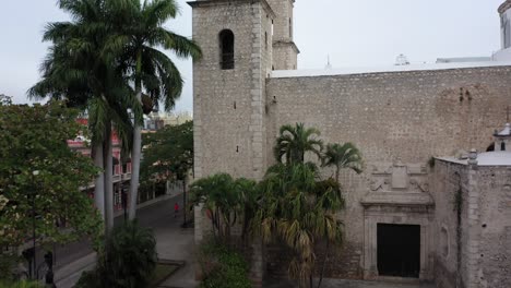 cámara aérea saliendo de detrás de una estatua en el parque hidalgo continuando por encima de la rectoría jesús en merida, yucatan, mexico