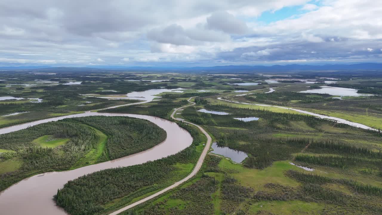 Stunning aerial view of winding river cutting through lush green landscape and forests in Alaska, perfect for travel or adventure content, inspiring exploration