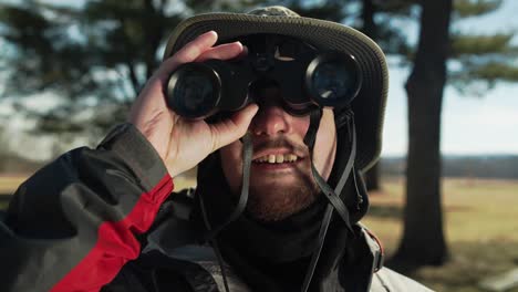 man out in nature taking photographs and looking with his binoculars