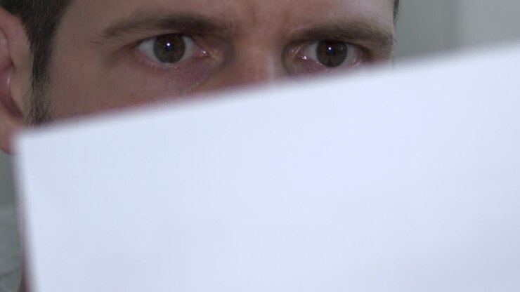 Close shot of male eyes reading and reacting to shocking paper document