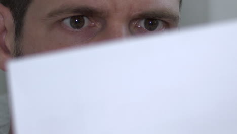 close shot of male eyes reading and reacting to shocking paper document