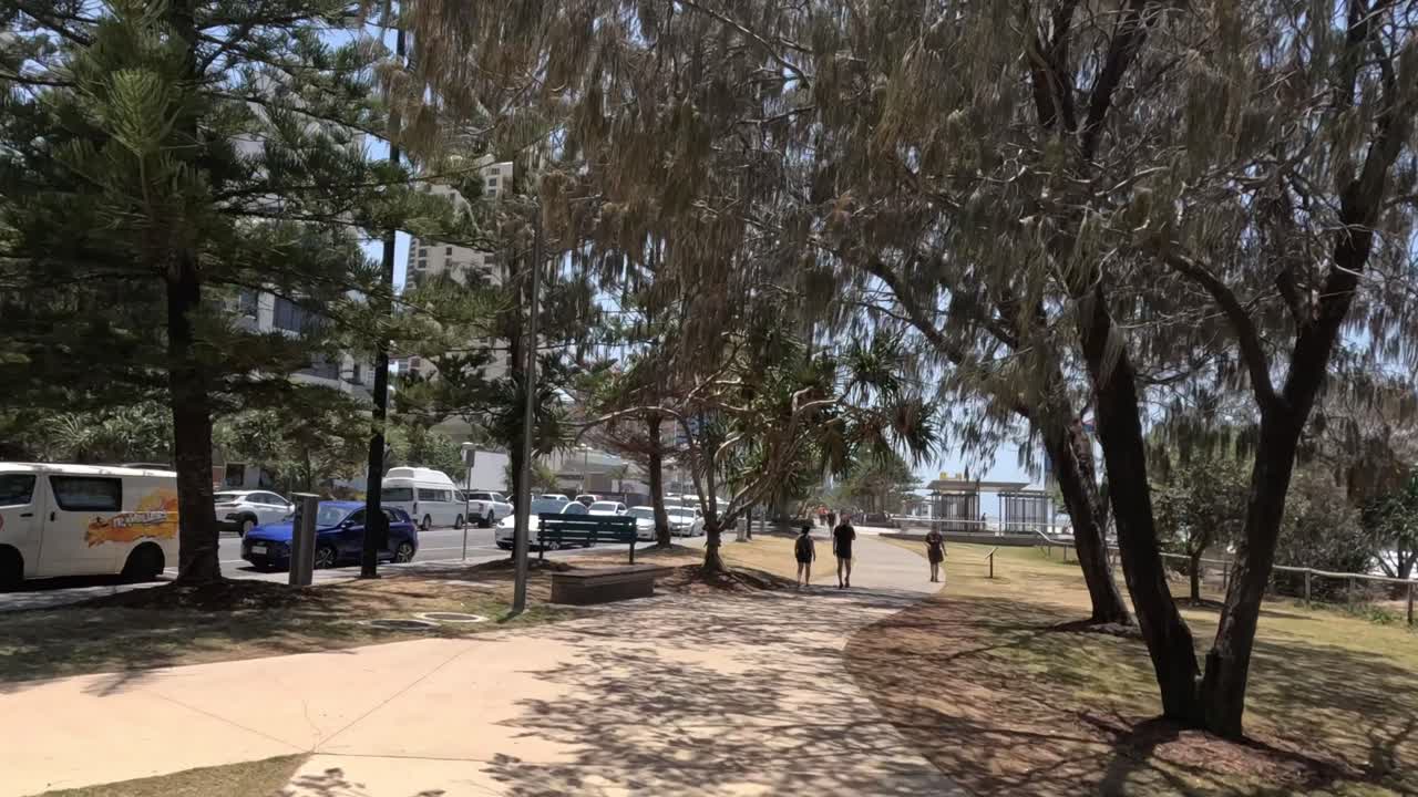 personas caminando en un parque urbano soleado cerca de los edificios