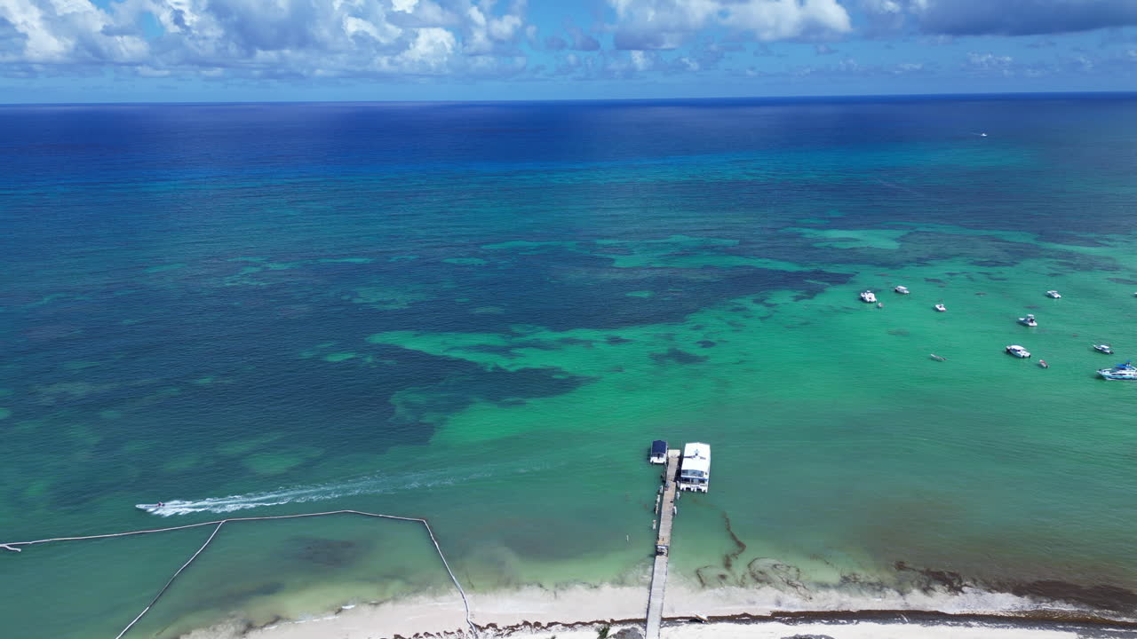 Drohnenaufnahme einer weißen Sandküste mit kristallklarem Meer und Resorts