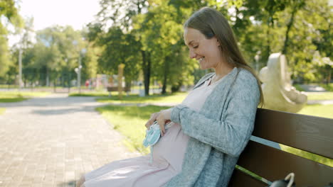 pregnant woman in park with baby clothes