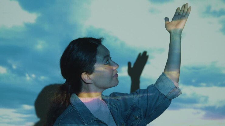 Woman Visiting Immersive Art Exhibition With Images Of Clouds Being Projected Onto Her Face