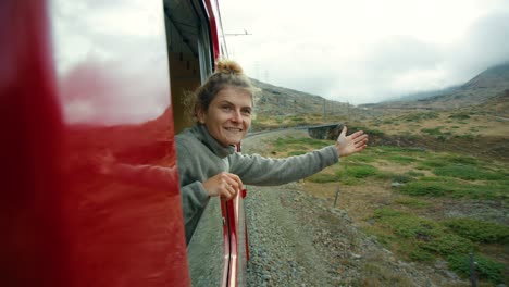 happy female traveller lean out of train window