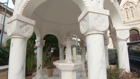 cenador de fuente de piedra de mármol blanco con gran cruz en la catedral de agia napa, limassol, chipre - tiro de seguimiento de órbita amplia