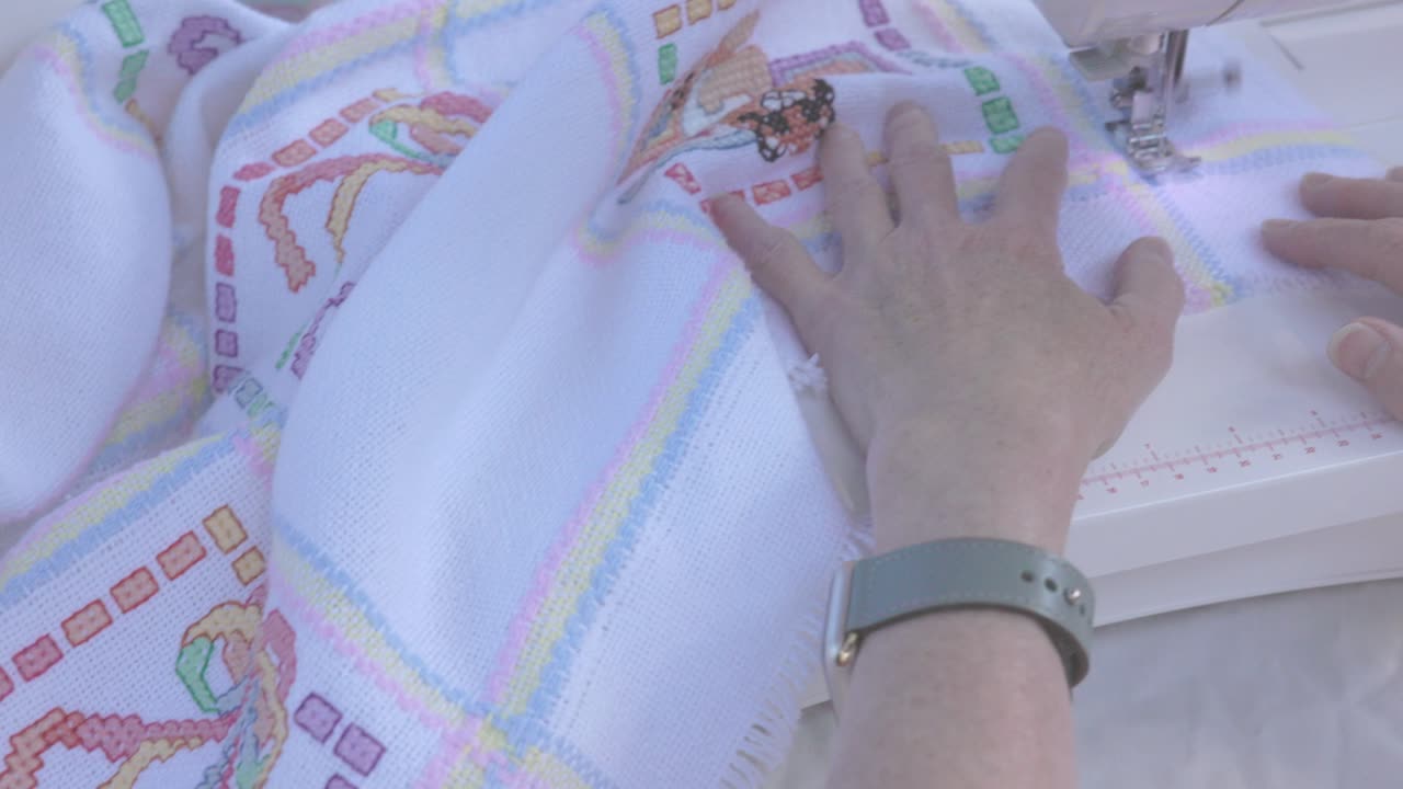 Panning shot of pictures stitched onto a baby blanket at a seamstress