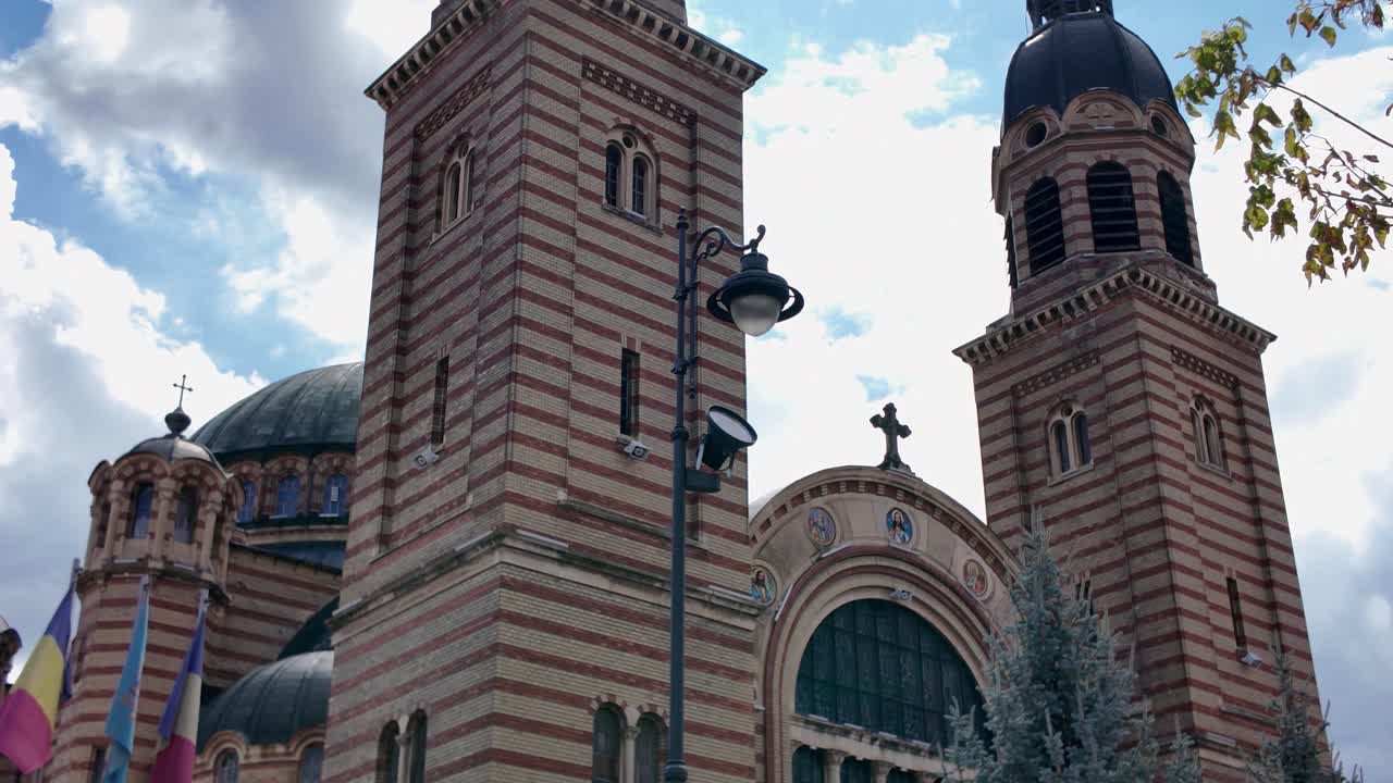 Smooth upward pan revealing the ornate façade and twin towers of the Holy Trinity Orthodox Cathedral in Sibiu, Romania