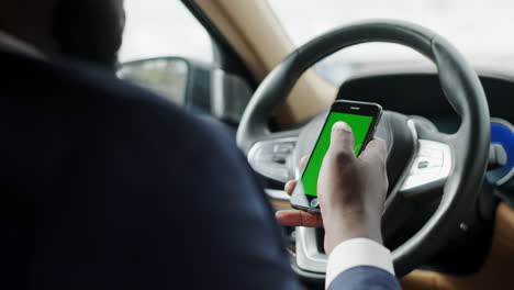 vista trasera de un hombre usando el teléfono de pantalla verde en el coche. hombre africano sentado con el teléfono