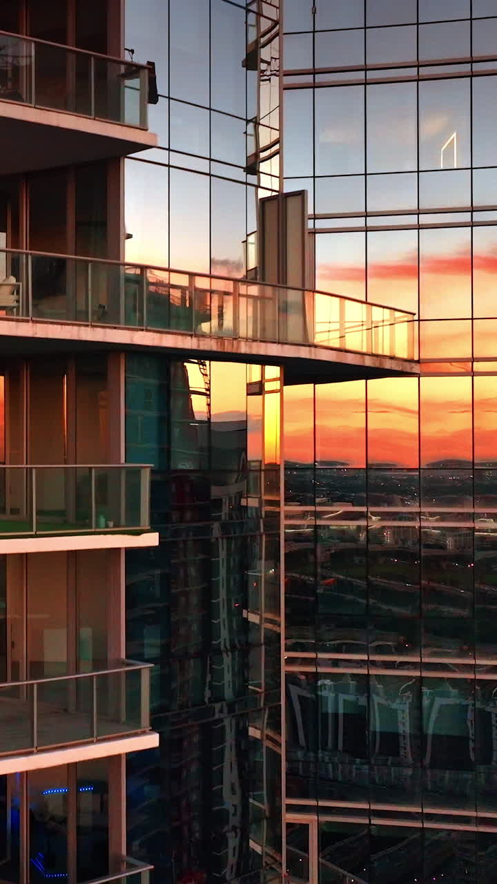 Luz dorada del atardecer reflejándose en las ventanas de espejo de un bloque de apartamentos. Edificio residencial moderno en Miami, Estados Unidos. Video vertical.