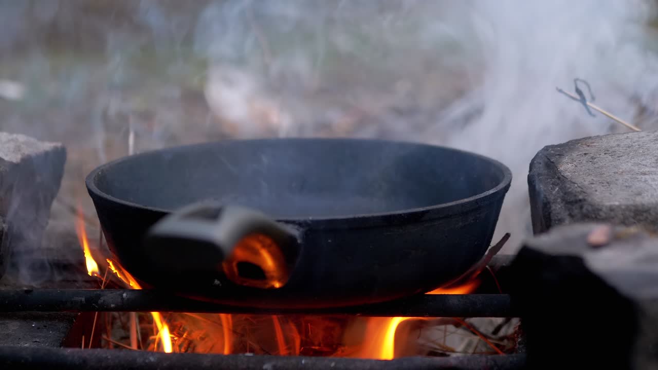 Padella fumante su un falò ardente nel bosco. Primo piano.