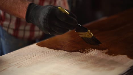 applying wood stain to a plank