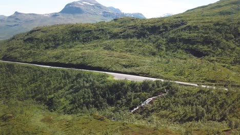 Dolly-shot-of-a-car-driving-on-a-mountain-road-on-a-sunny-summer-day