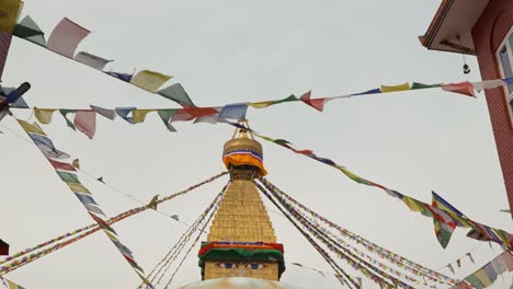 panning clip from looking upwards at strings of prayer flags, moving to holy buddhist temple