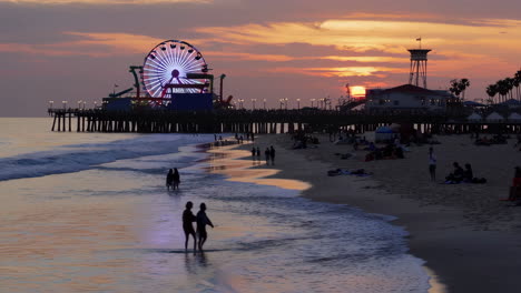 sunset at a lively beach pier with a ferris wheel