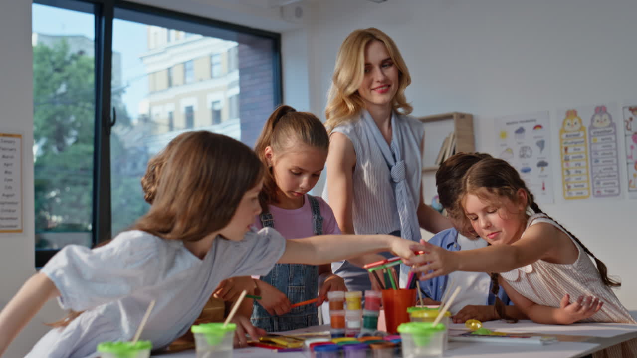 Teacher helping students art activity at primary school. Engaged pupils creating