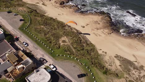 turista disfrutando del parapente desde los acantilados junto a la playa en el pueblo de la pedrera en la costa atlántica, uruguay